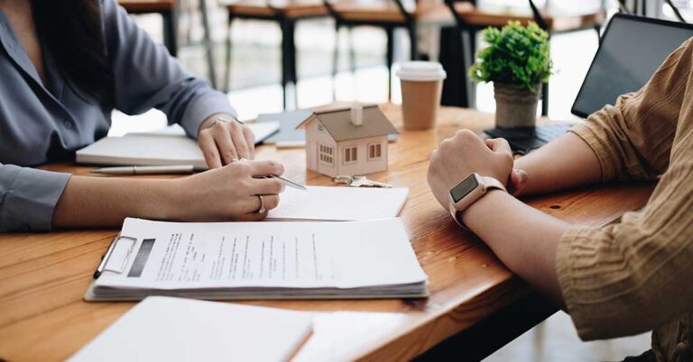 Homeowner reviewing repair notes and disclosure papers at a kitchen table in an older house.